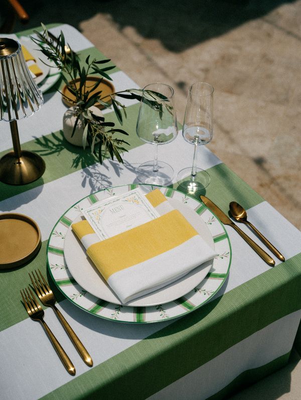 Elegant table setting with Vintage Stripe Palm tablecloth rental showcasing bold green stripes and coastal café charm