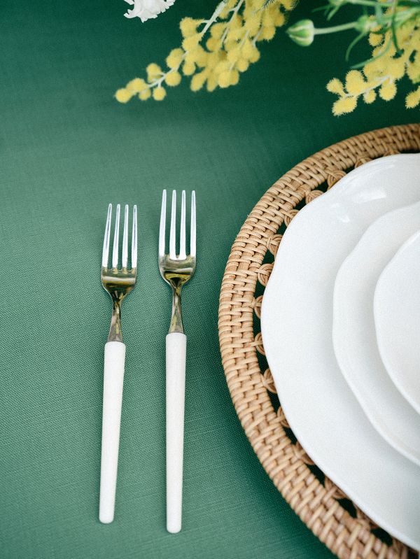 Earthy green tablecloth paired with rattan charger